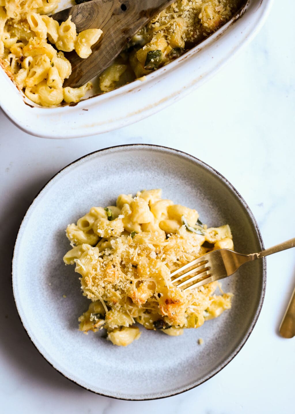 Baked Mac and cheese with cheddar and poblano peppers in a gray bowl with a gold fork.