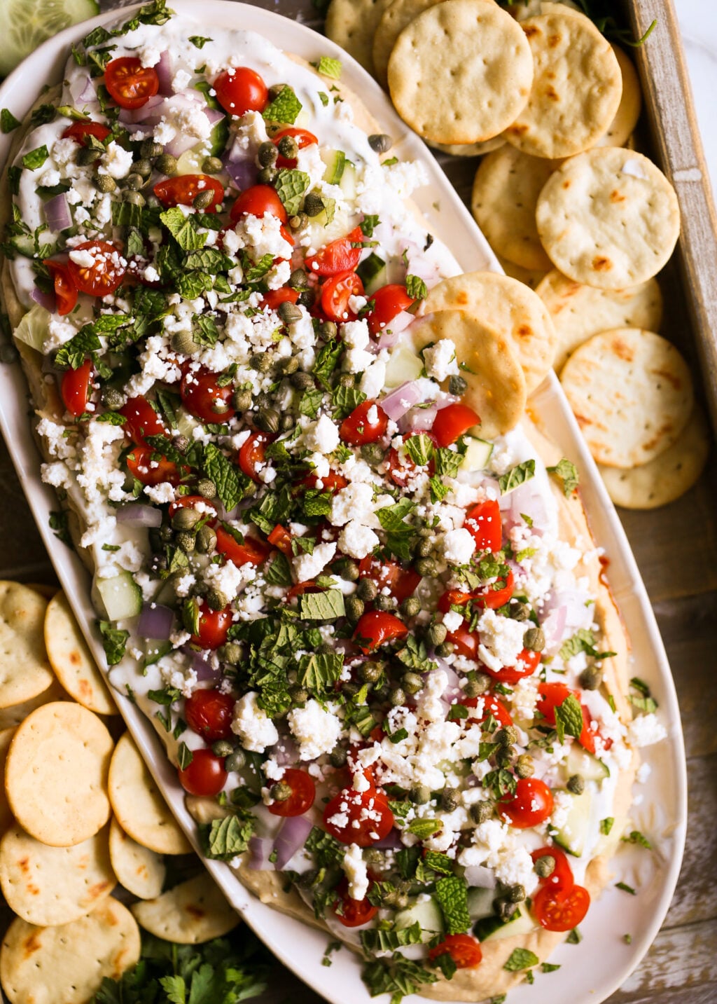 Easy Greek layered dip with hummus, tzatziki, tomatoes, cucumbers, feta, and herbs, perfect for a healthy appetizer recipe.