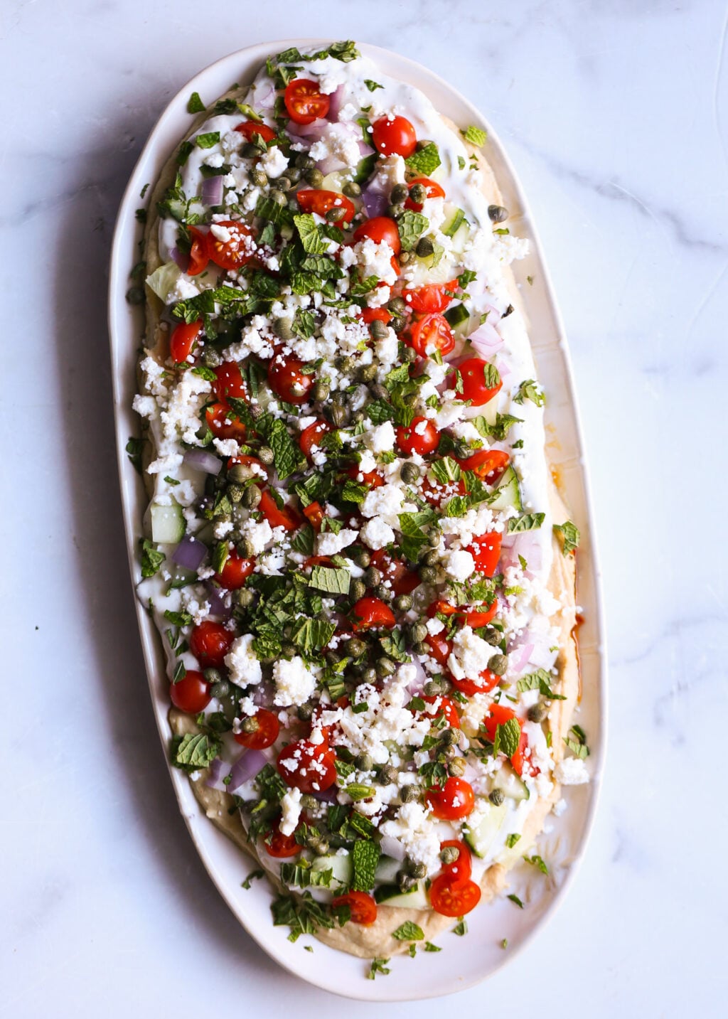 Easy layered Greek dip with creamy hummus, tzatziki, tomatoes, cucumber, feta, and fresh herbs, perfect healthy appetizer recipe.