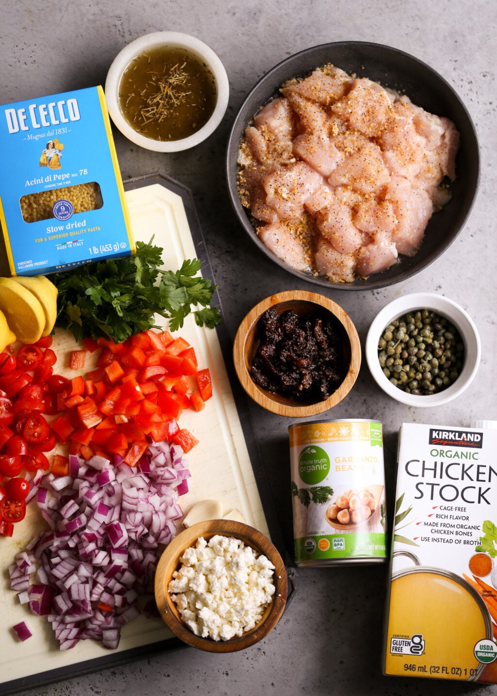 Easy Mediterranean chicken orzo casserole ingredients including diced chicken, orzo pasta, tomatoes, peppers, feta, and chicken stock.