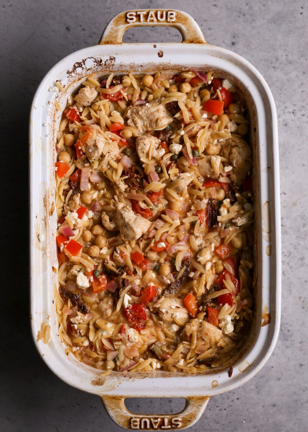 Easy Mediterranean chicken orzo casserole with chickpeas, tomatoes, red onion, and feta, a healthy one-pan dinner recipe.
