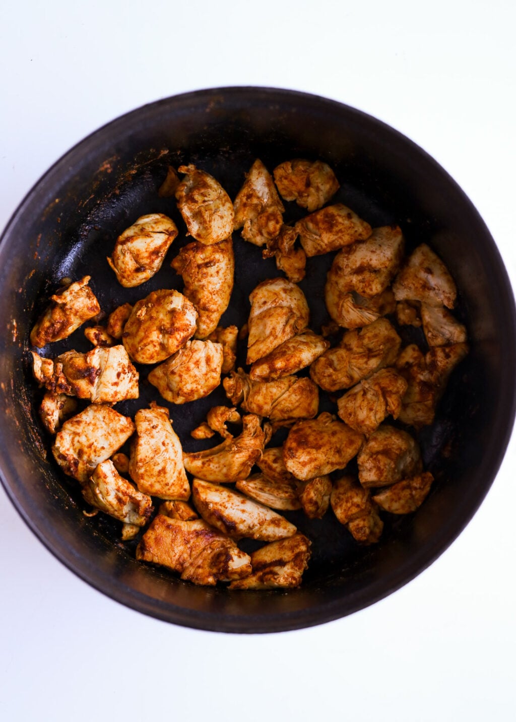 Browned chicken cubes seasoned with paprika in a skillet, forming the base for creamy chicken poblano soup—easy dinner recipe