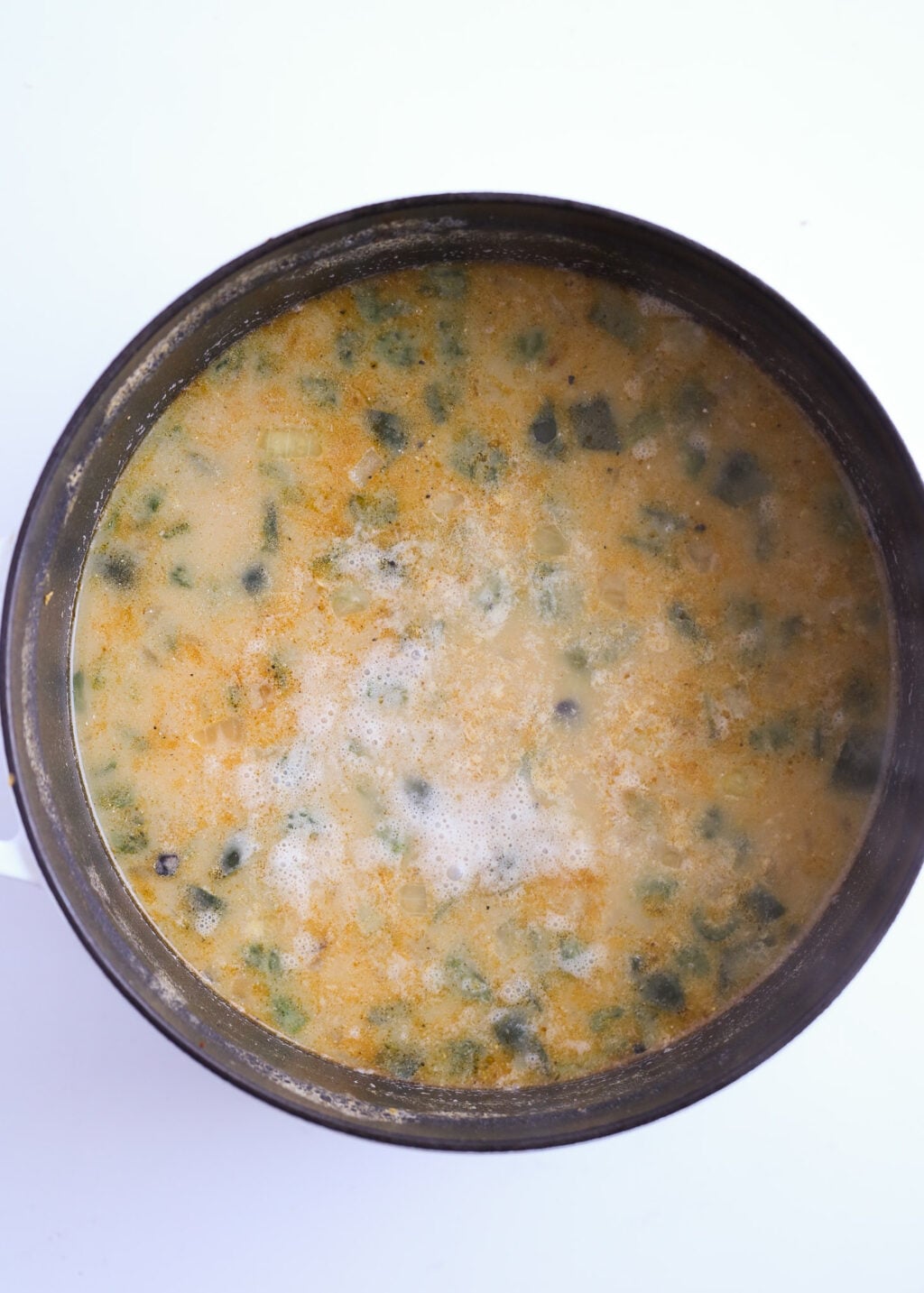 Creamy chicken poblano soup with corn and green peppers simmering in a pot, easy dinner recipe.