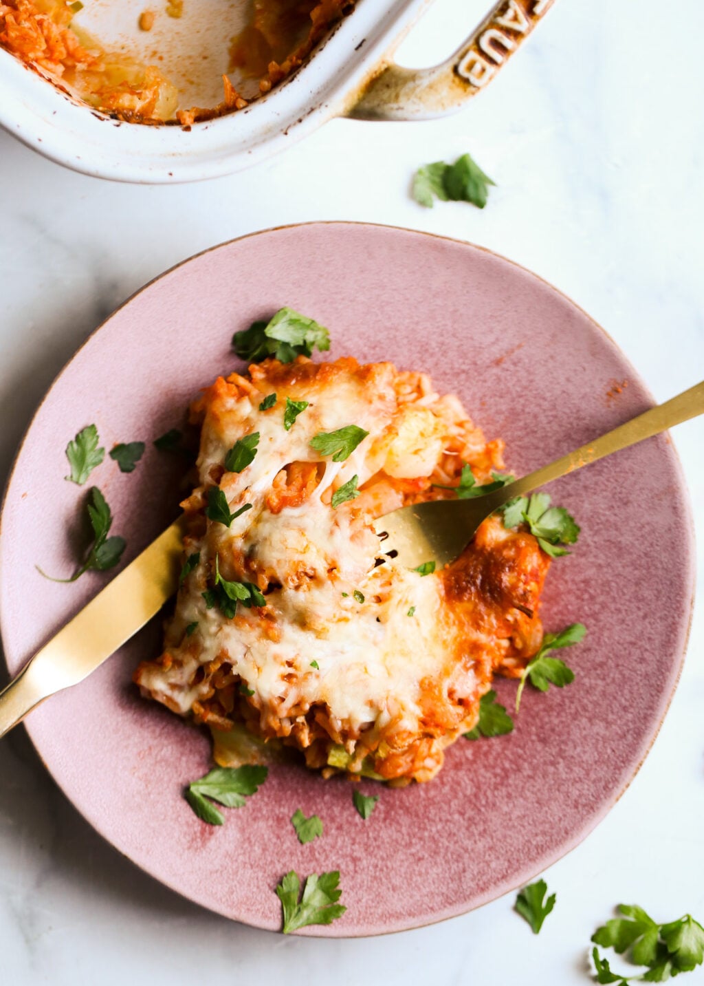 Easy unstuffed cabbage casserole recipe with cheesy tomato sauce, ground meat, rice, parsley garnish for dinner.