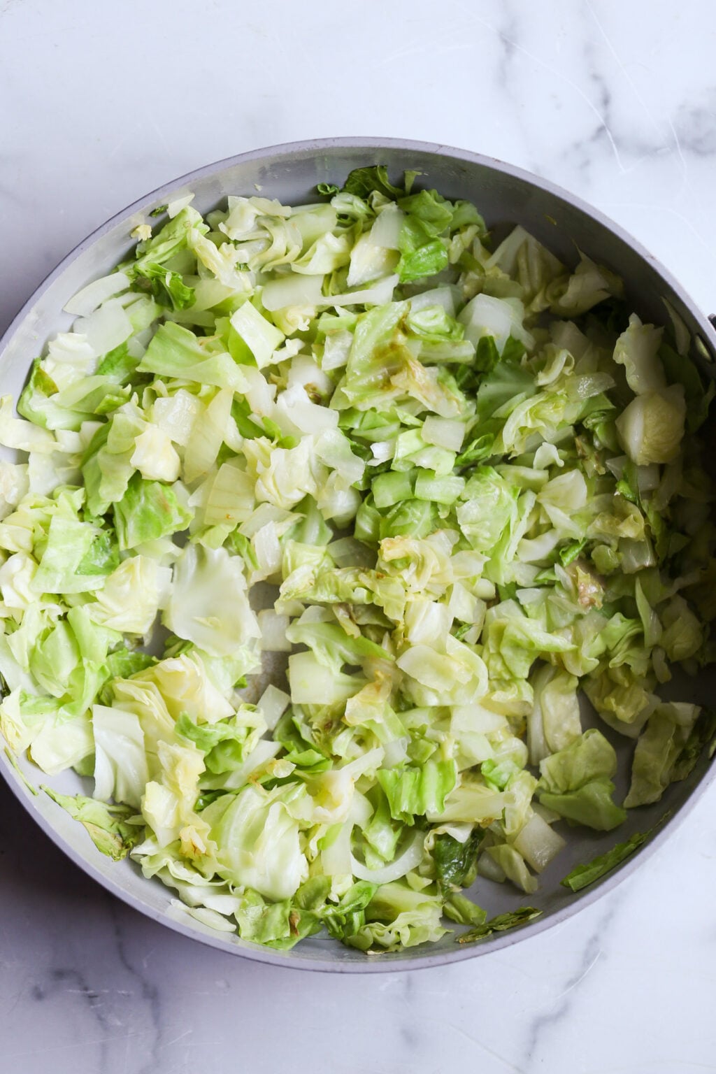 Chopped green cabbage in a round pan, for sauteing easy unstuffed cabbage casserole for dinner.