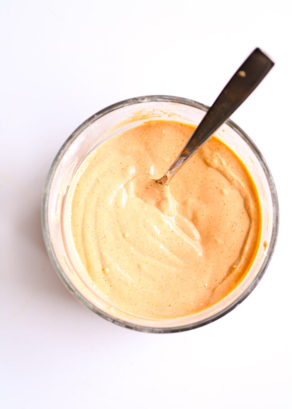 Creamy cheeseburger casserole sauce in a glass jar with a spoon, for healthy cheeseburger casserole with potatoes.