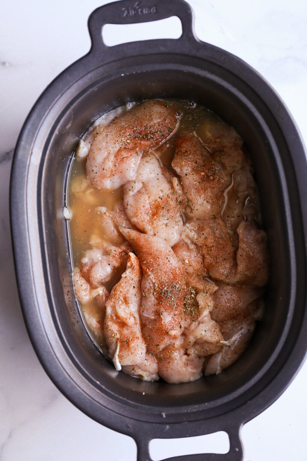 Easy slow cooker chicken recipe: chicken stock and lemon juice over the raw chicken.