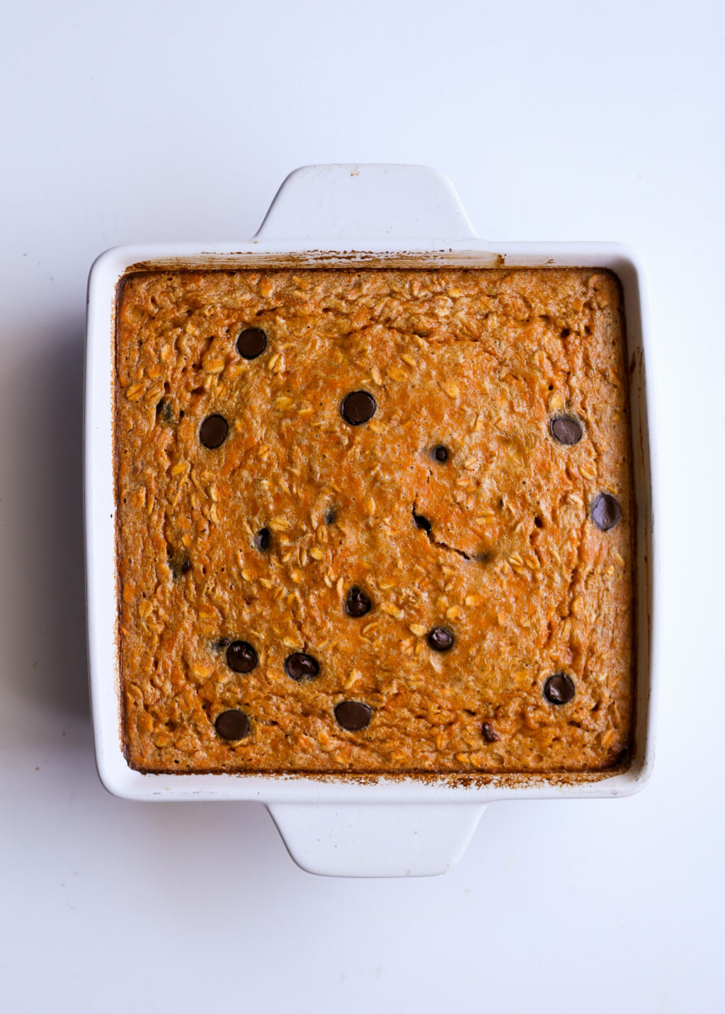 Sweet potato chocolate chip breakfast casserole baked in a white square dish. Golden crust with visible chocolate chips.
