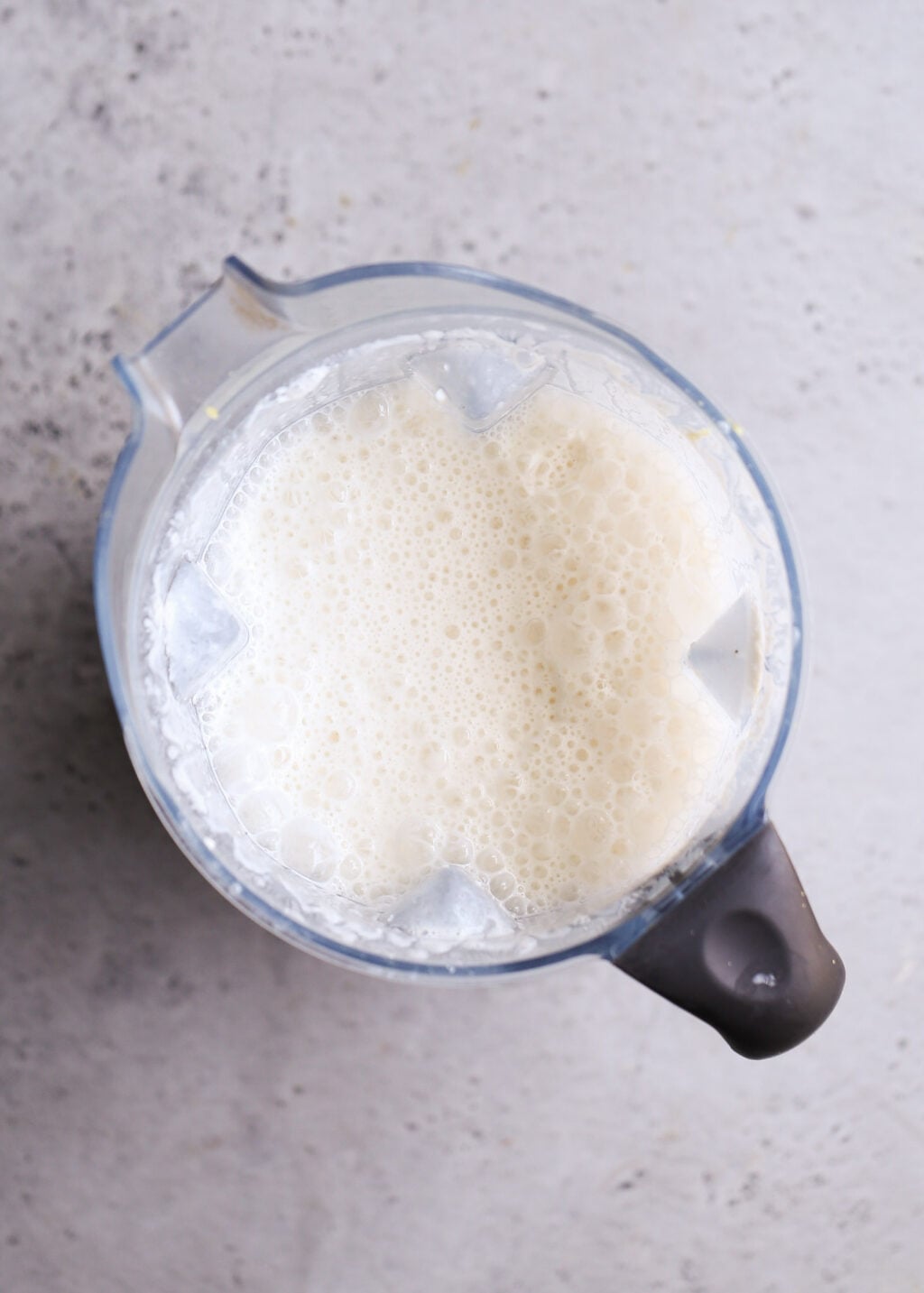 Top-down view of blender jar with frothy cottage cheese sauce for no-boil chicken pasta casserole (dump-and-bake) recipe.