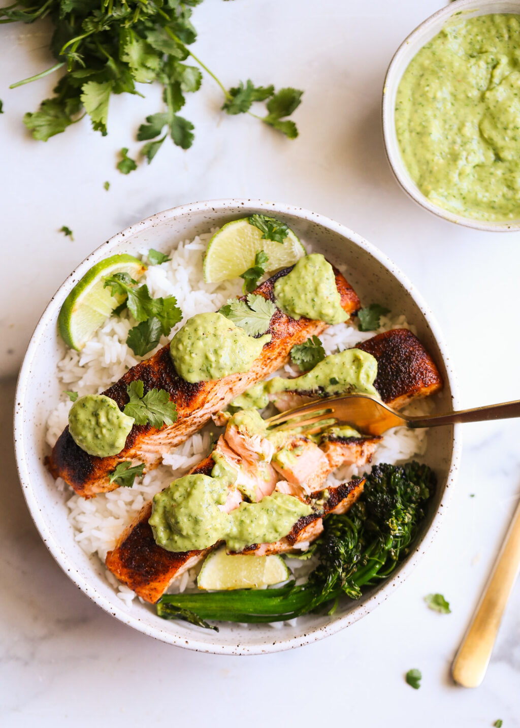 Sheet-pan blackened salmon over white rice, topped with cilantro avocado pesto, lime slices, and greens