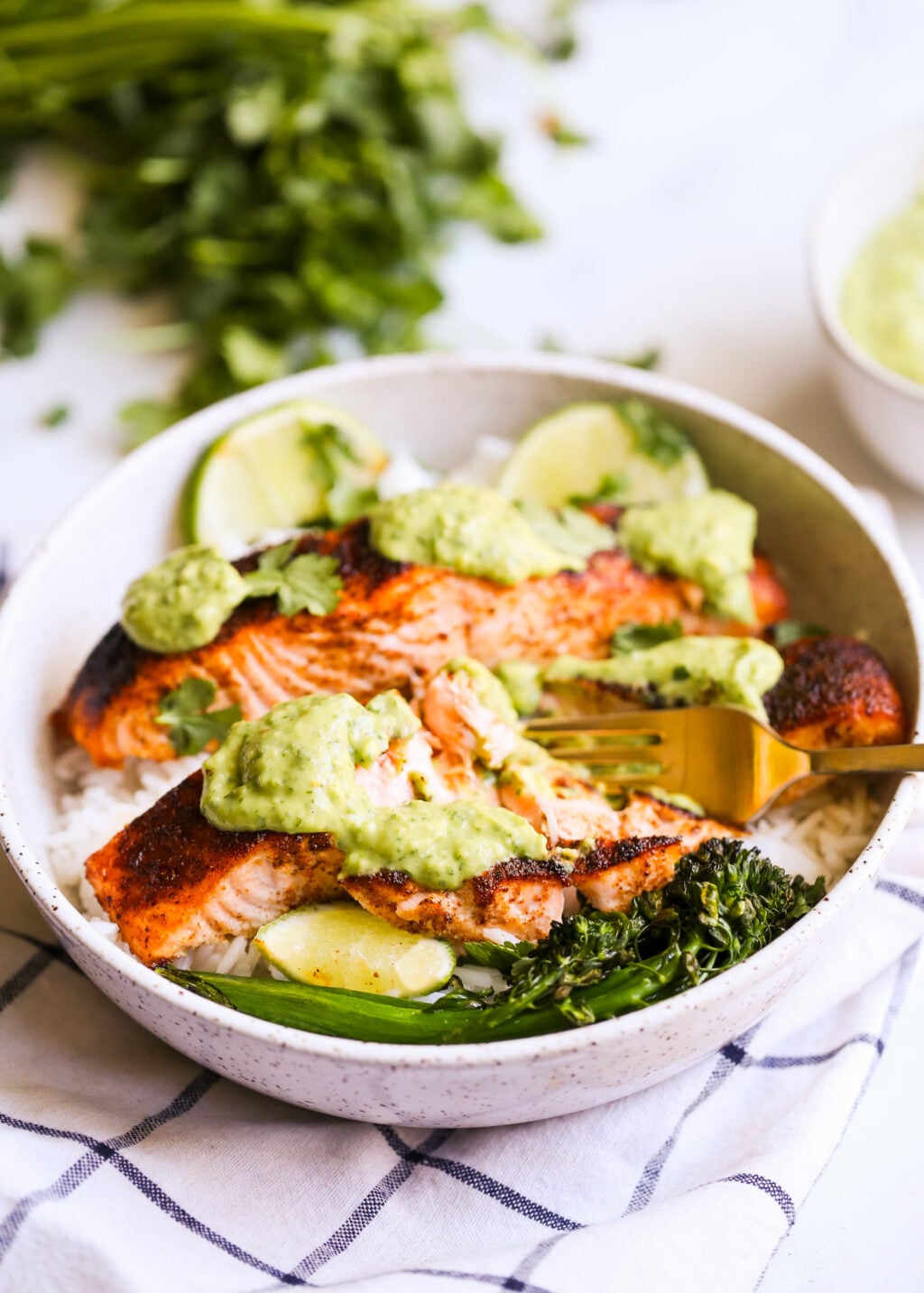 Blackened salmon bowl with cilantro-avocado pesto, lime wedges, and avocado chunks over white rice