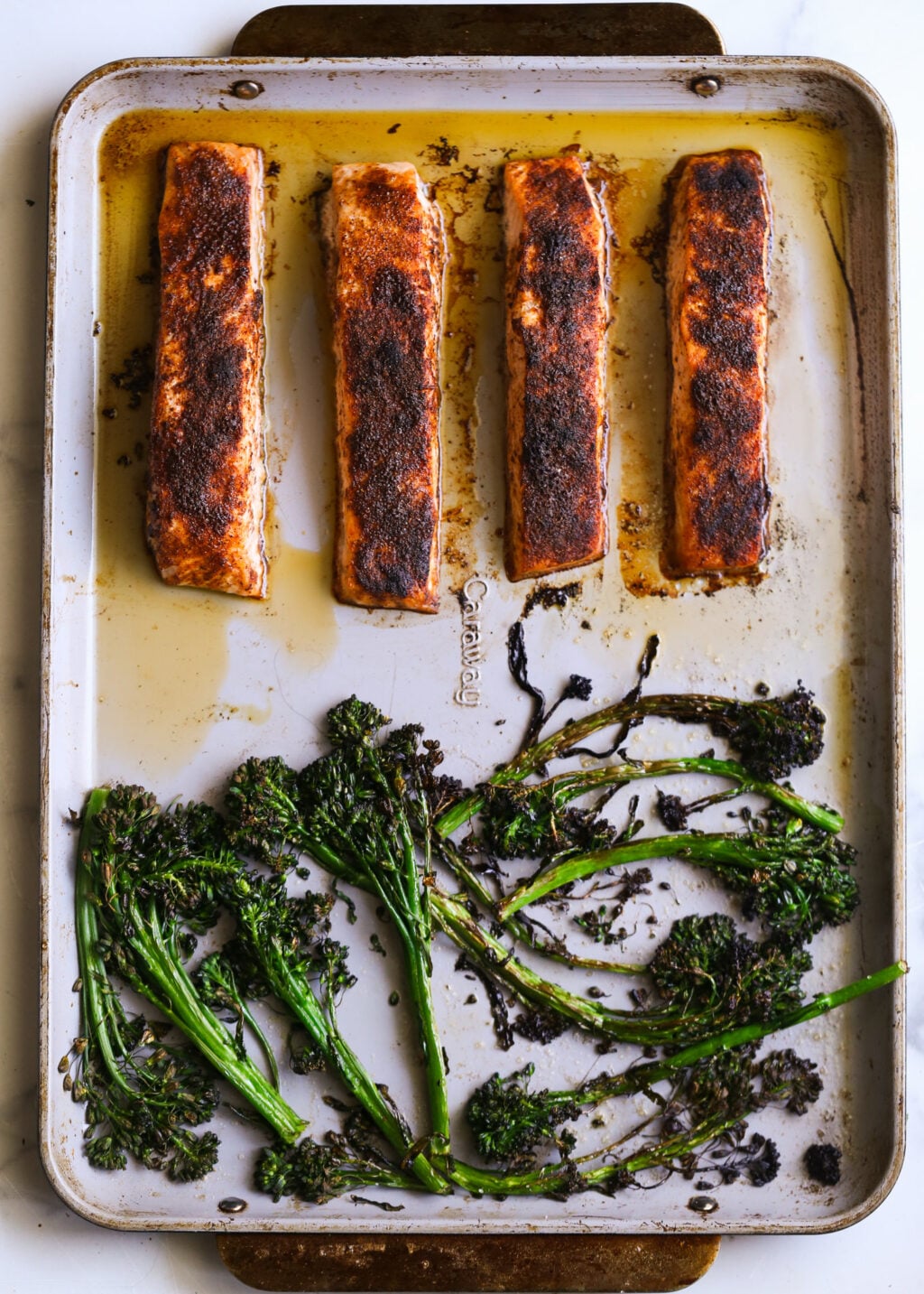 Sheet-pan blackened salmon fillets with charred broccoli rabe greens on a baking sheet, ready for cilantro-avocado pesto.