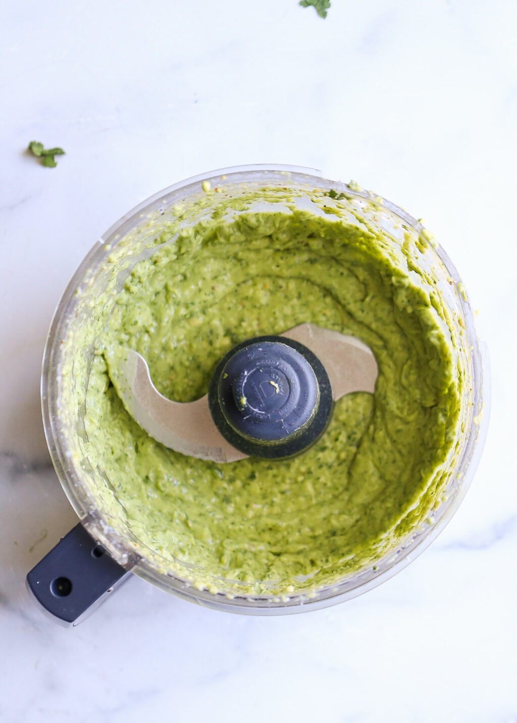 Creamy cilantro-avocado pesto blended in a food processor, part of the sheet-pan blackened salmon recipe.