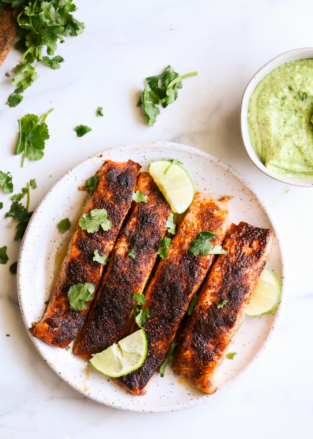 Sheet-pan blackened salmon fillets with lime wedges and cilantro, served with cilantro-avocado pesto.