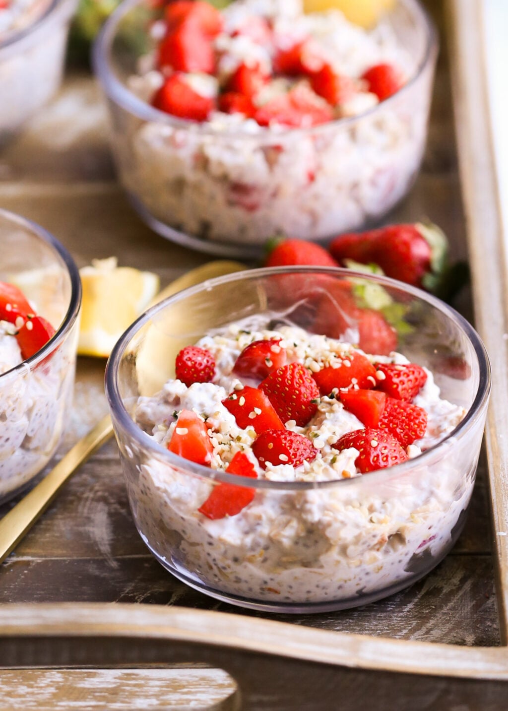Strawberry lemon overnight oats in clear bowls topped with fresh strawberries and sesame seeds—a make-ahead breakfast parfait.