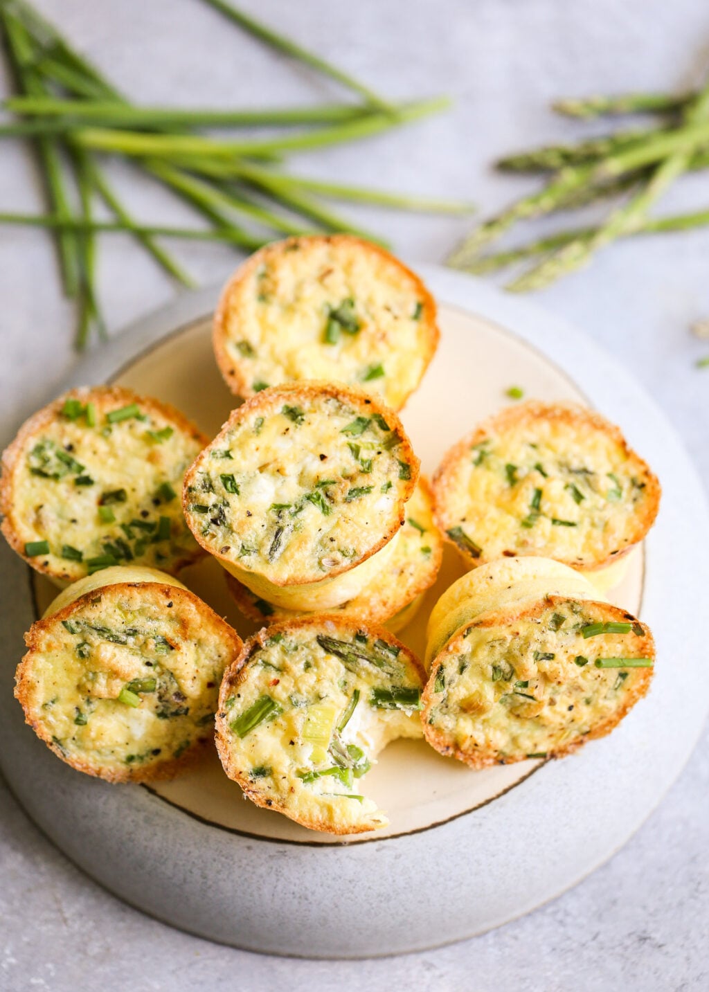 Baked asparagus and feta egg muffins in muffin cups, golden edges and high-protein breakfast bites for meal prep.