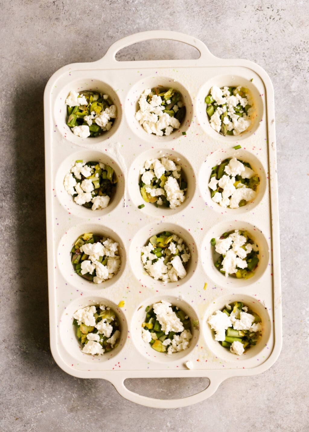 Asparagus and feta egg muffin cups for high-protein meal prep, baked in a 12-cup muffin tin.