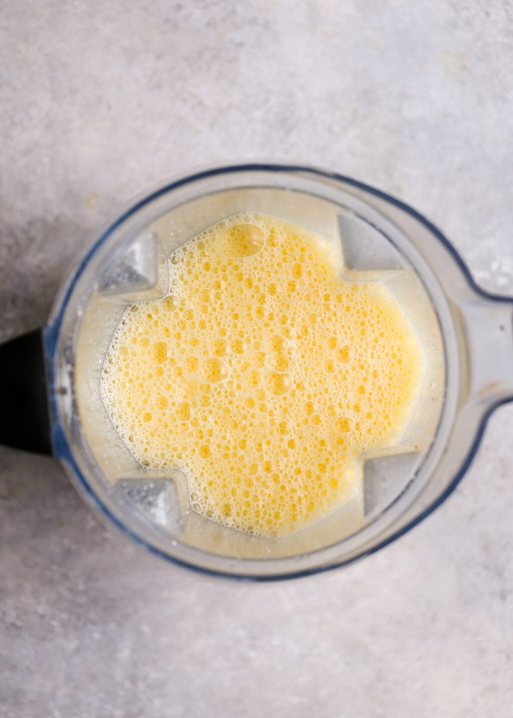Blender with foamy yellow egg mixture for high-protein asparagus and feta egg muffins—meal prep recipe.