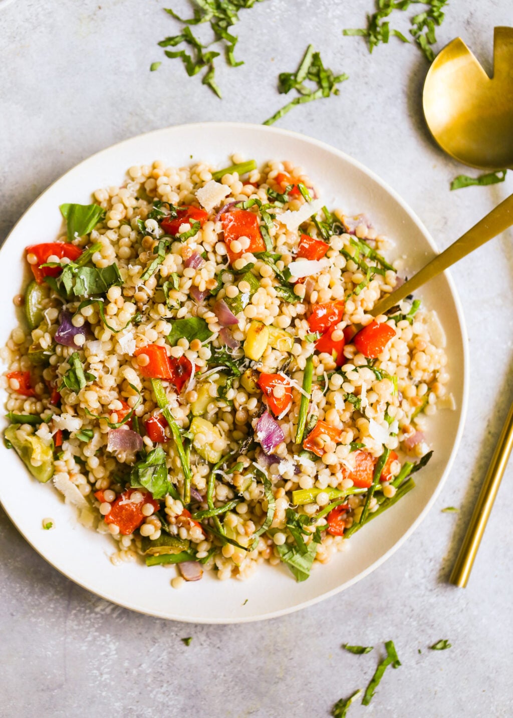 Colorful Israeli couscous salad with roasted vegetables and herbs topped with Parmesan for an easy Mediterranean‑style side.