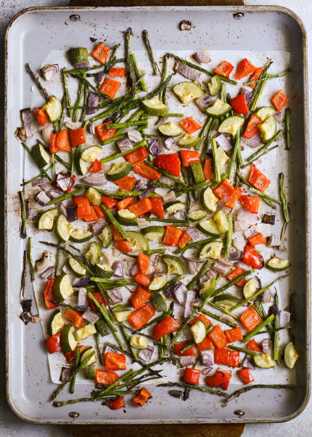 Roasted zucchini, bell peppers, asparagus, and red onion on a sheet pan for the Israeli couscous salad.