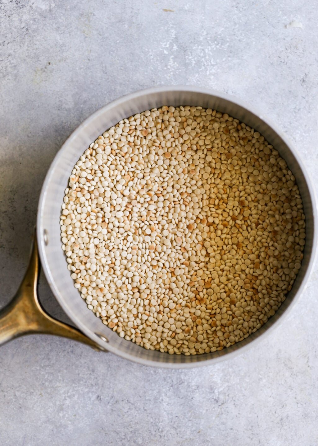 Uncooked couscous pearls in a saucepan before boiling for the Israeli couscous salad recipe.