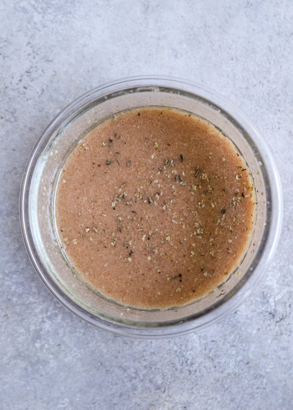 Light red wine vinaigrette with herbs mixed in a glass bowl for the Israeli couscous salad recipe.