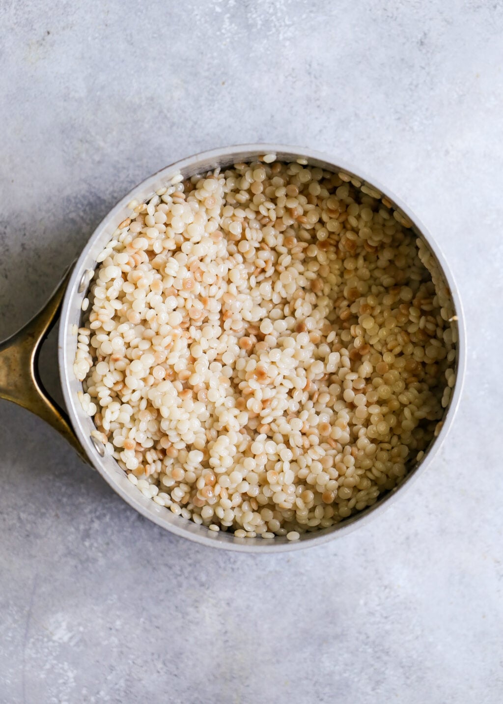 Cooked Israeli couscous in a saucepan, ready to mix into the roasted vegetable salad.