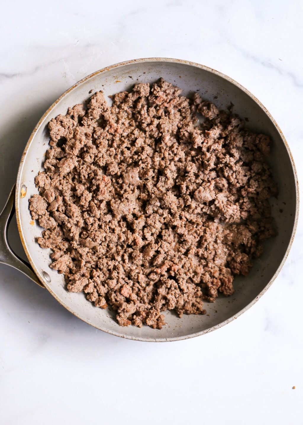 Browned ground beef cooked in a skillet as the protein base for healthy burger bowls.
