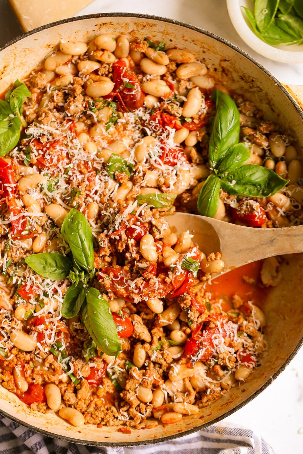 Turkey and white bean skillet with cherry tomatoes, basil, and Parmesan served as a simple weeknight dinner.