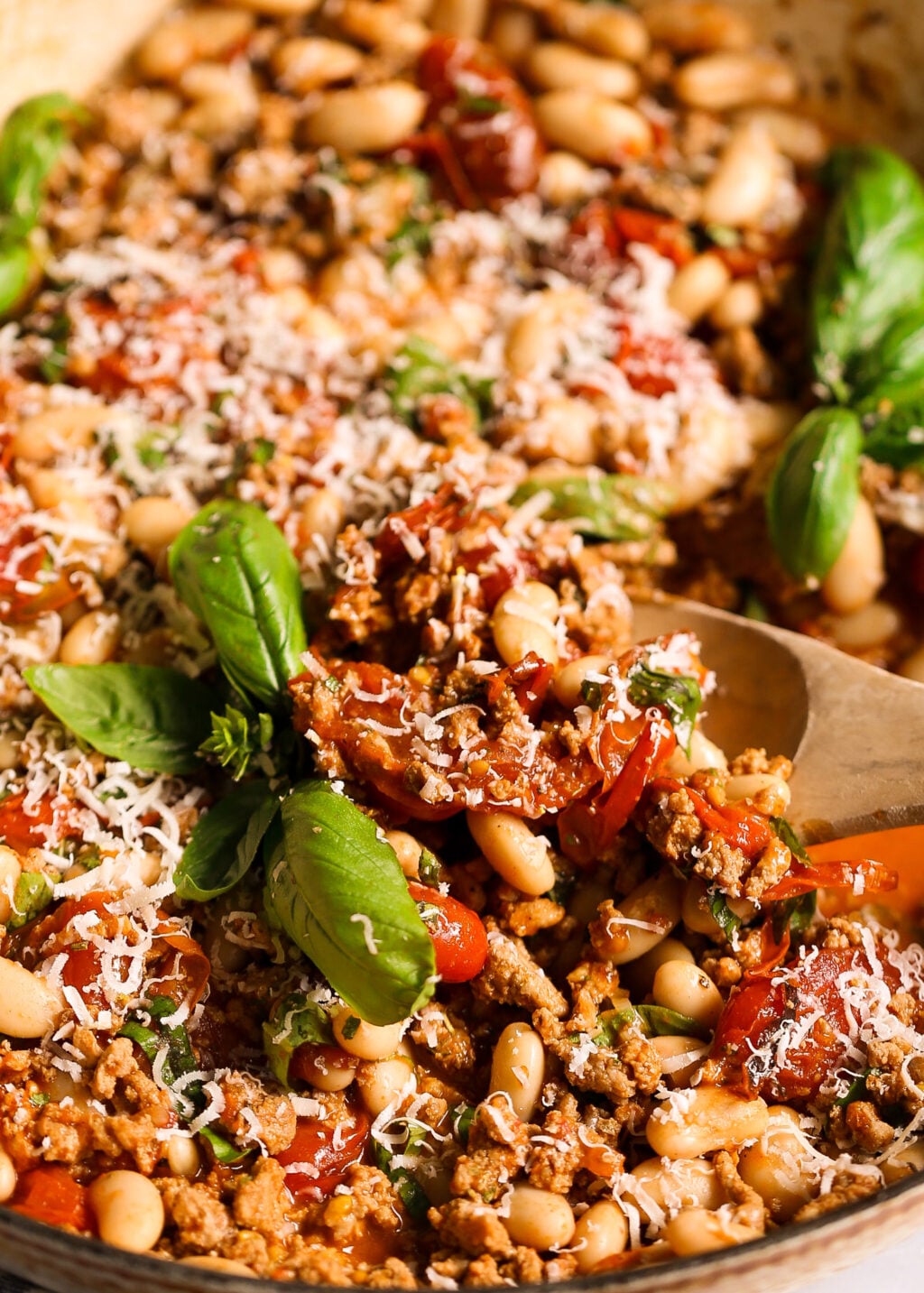 Turkey and white bean skillet mixed with burst cherry tomatoes, fresh basil, and grated cheese.