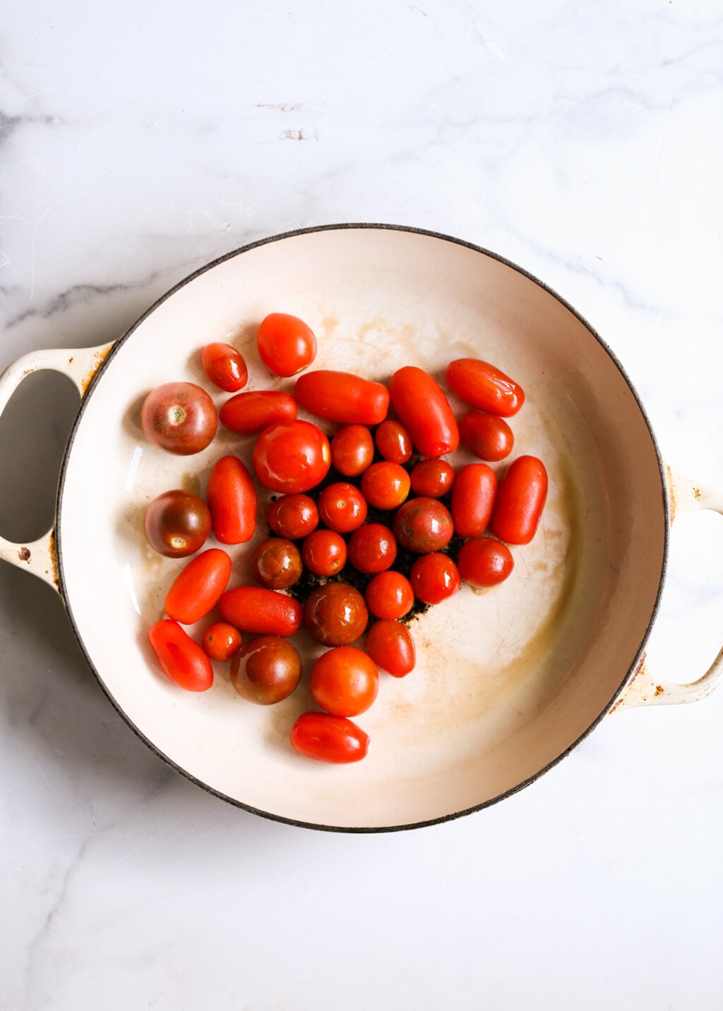 Fresh cherry tomatoes prepared in a skillet as the base for burst tomato sauce.